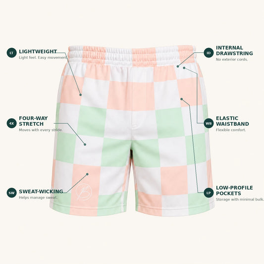 A pair of lightweight athletic shorts with a pastel pink, white, and mint green checkered pattern, shown with feature callout labels on a light beige background.