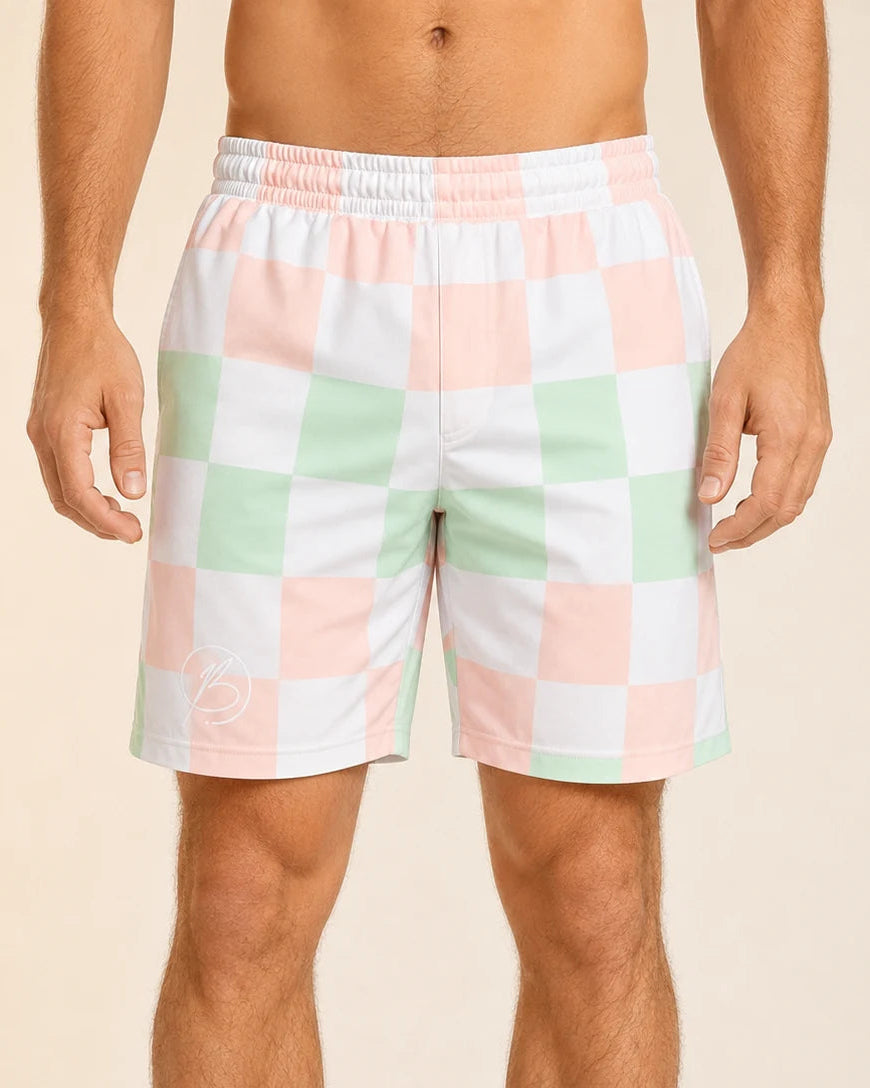 A man wearing pastel checkered shorts with a white elastic waistband, featuring a pattern of pink, mint green, and white squares, against a solid beige background.