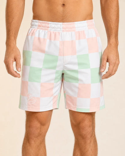 A man wearing pastel checkered shorts with a white elastic waistband, featuring a pattern of pink, mint green, and white squares, against a solid beige background.