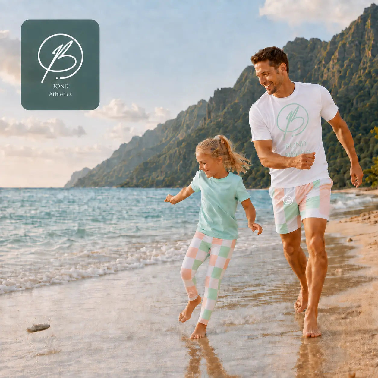 A man and a young girl run along a sandy beach shoreline wearing matching Bond Athletics athletic wear. The man wears a white t-shirt and pastel striped shorts, while the girl wears a light mint green t-shirt and pastel checkered leggings.