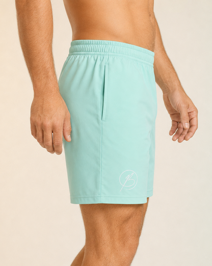 A man wearing light mint green athletic shorts, shown from the waist down against a plain beige studio background.