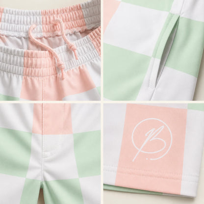 A four-panel close-up collage of pastel checkered shorts, showing the elastic drawstring waistband, side seam detail, front pocket area, and a white script logo printed on a soft pink square. The fabric pattern alternates white, pale mint green, and blush pink.