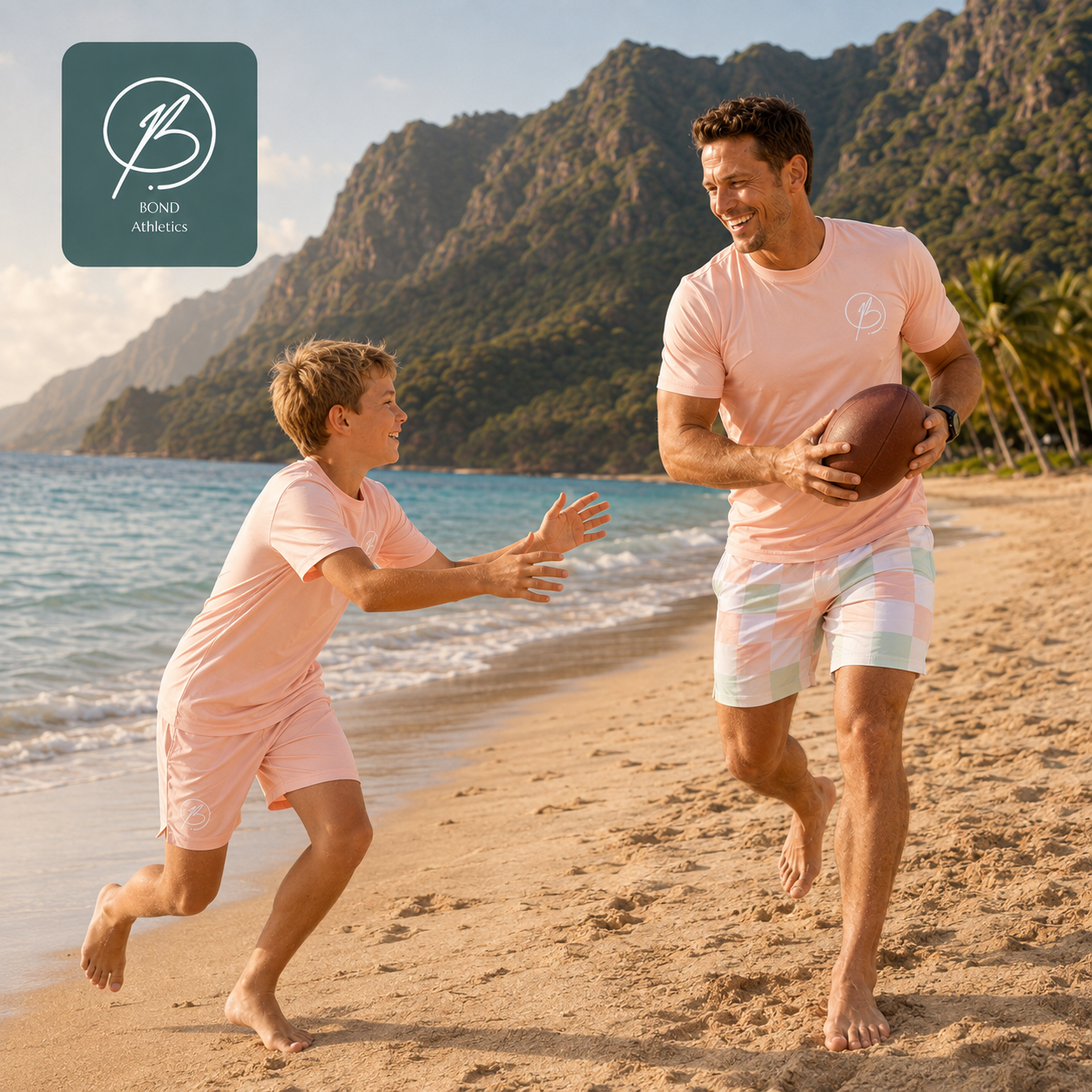 A father and son running and playing with a football on a sandy beach, both wearing matching light pink athletic t-shirts and shorts. A green 'ROAD ATHLETICS' brand logo is visible in the top-left corner.