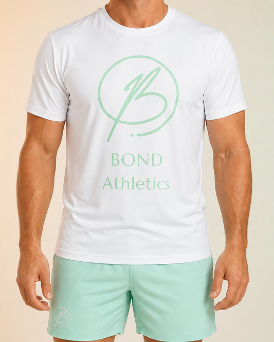A man wearing a white short-sleeve athletic T-shirt with a mint green 'Bond Athletics' logo on the chest, paired with mint green athletic shorts, shown against a soft beige-to-green gradient background.