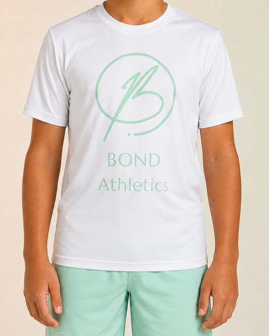 A child model wearing a white short-sleeve athletic t-shirt with a mint green 'BOND Athletics' logo on the chest, paired with mint green athletic shorts, set against a soft beige-to-green gradient studio background.