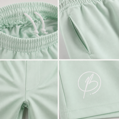 A four-panel close-up collage of mint green athletic shorts, showing the elastic waistband with white drawstrings, a side pocket, the leg opening, and a white script logo on the thigh.