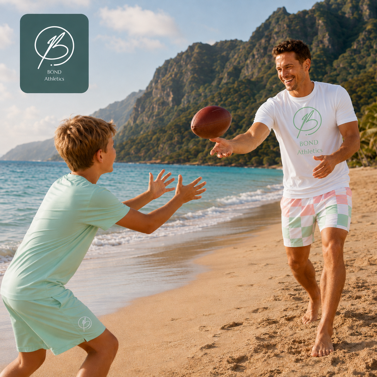 A man and a boy play catch with a football on a sandy beach with ocean and mountains in the background. Both are wearing matching light mint green Bond Athletics t-shirts and shorts sets.