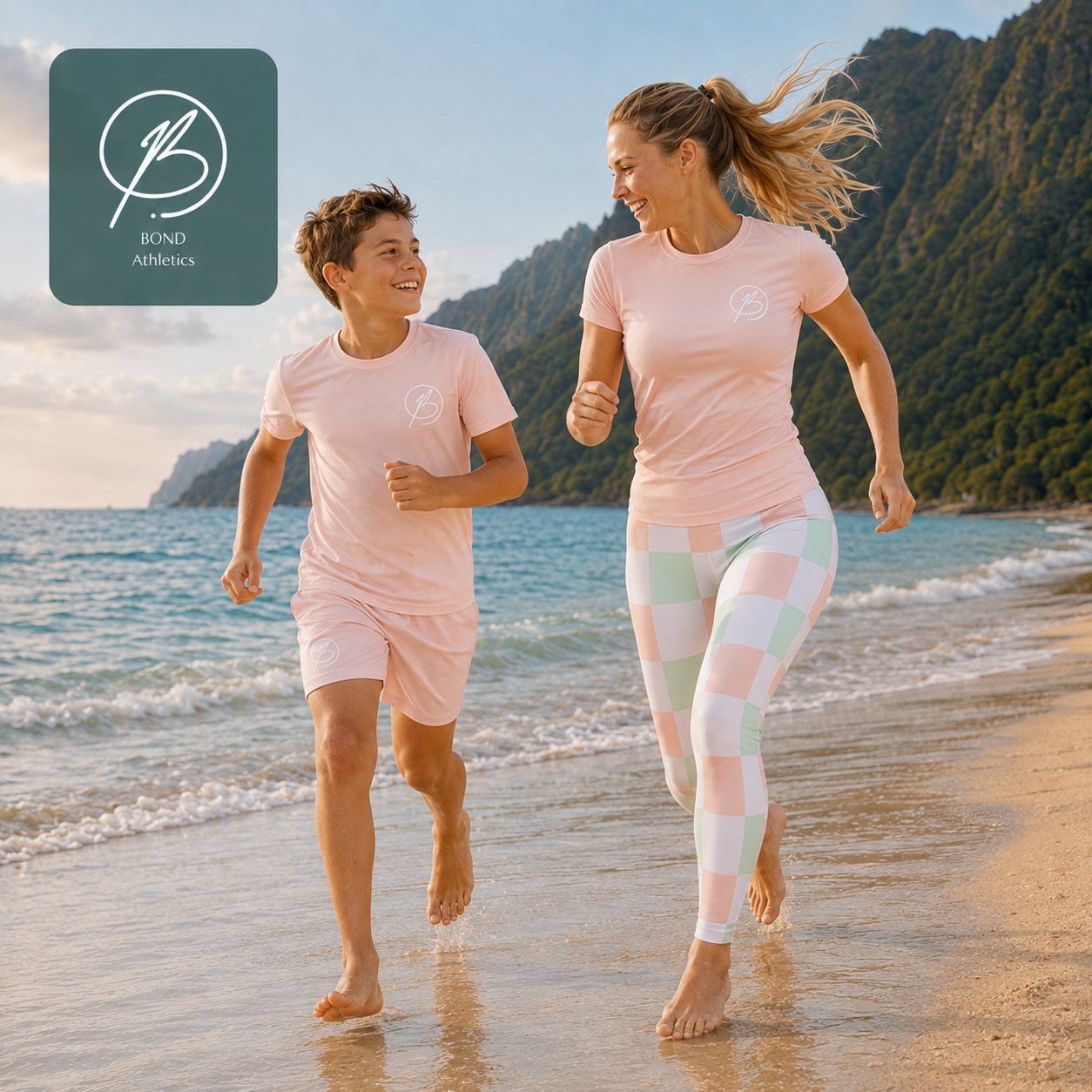 A woman and a boy running happily on a sandy beach wearing matching light pink athletic outfits. The woman also wears pastel checkered leggings in pink, mint, and white.
